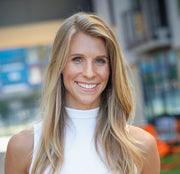 A woman with long, layered brown hair smiling at the camera, symbolizing wellness and positivity, aligned with WeNatal's health-focused products.